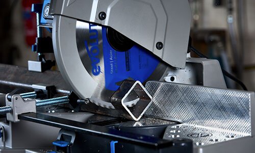 Blade of a mitering chop saw cutting though a hollow metal bar