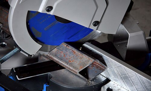 Image of a circular blade cutting through a hollow square metal tube.