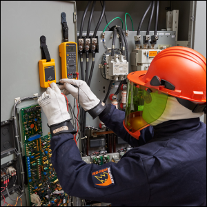 Technician in full PPE using a Fluke Proving Unit