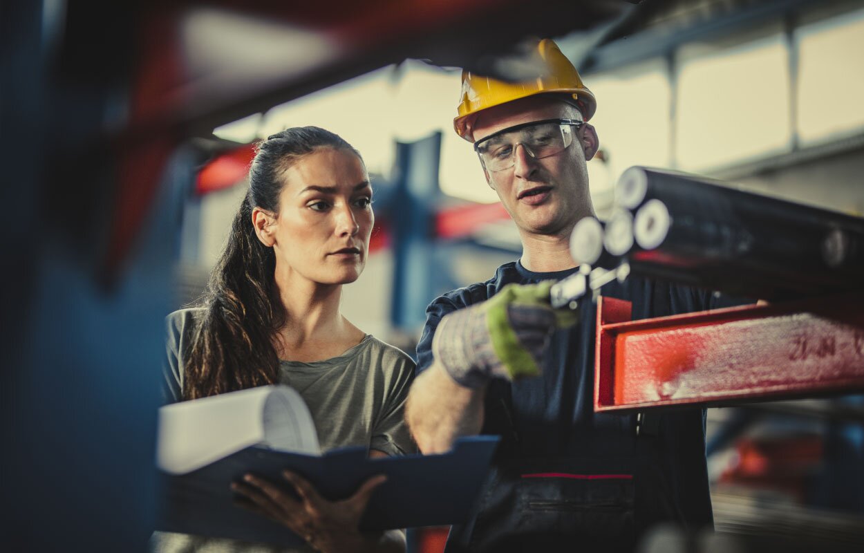 Coworkers (male and female) in a warehouse looking at a machine