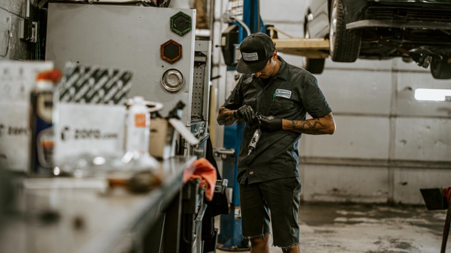 worker in an auto shop adjusting a tool