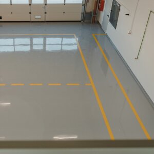 Cement floor with safe traffic routes marked with bright yellow tape