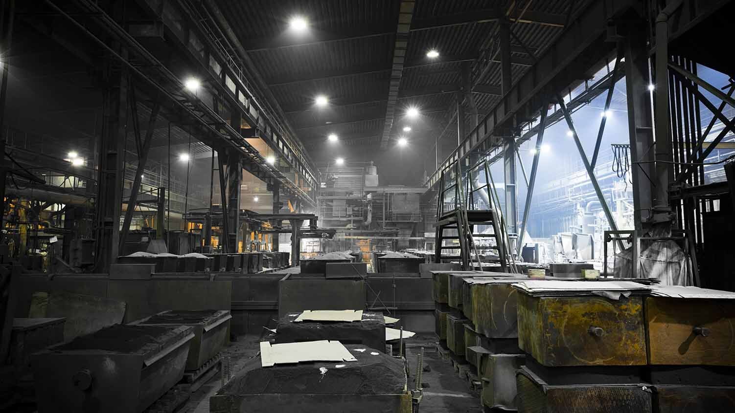 Dim and dark image of the interior of a steel manufacturing plant with poor lighting.