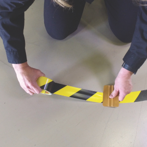 image of a worker laying down floor tape in a curve