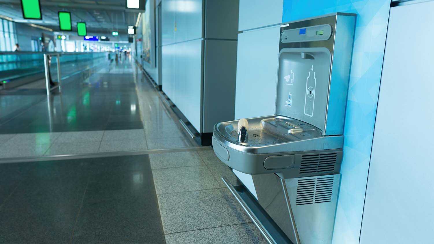 Image of a water bottle filling station at the side of a long hall.