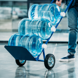 Image of three 5-gallon water jugs stacked on their sides on a hand truck dolly.