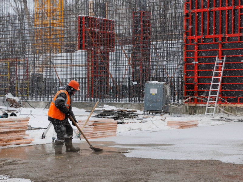 worker wearing overalls and leveling concrete at a construction site