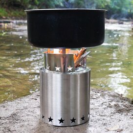 Pot of boiling water on top of a Starfire Camp Stove next to a river.