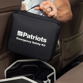 A man picks up his emergency car kit in his backseat.