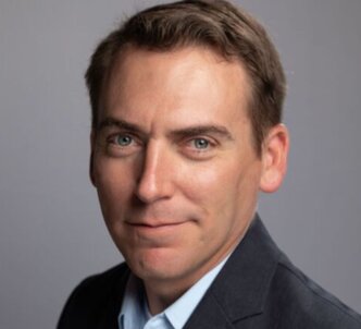 A man transports a 4Patriots portable solar generator at a campsite, highlighting its use for providing power while camping off-grid.