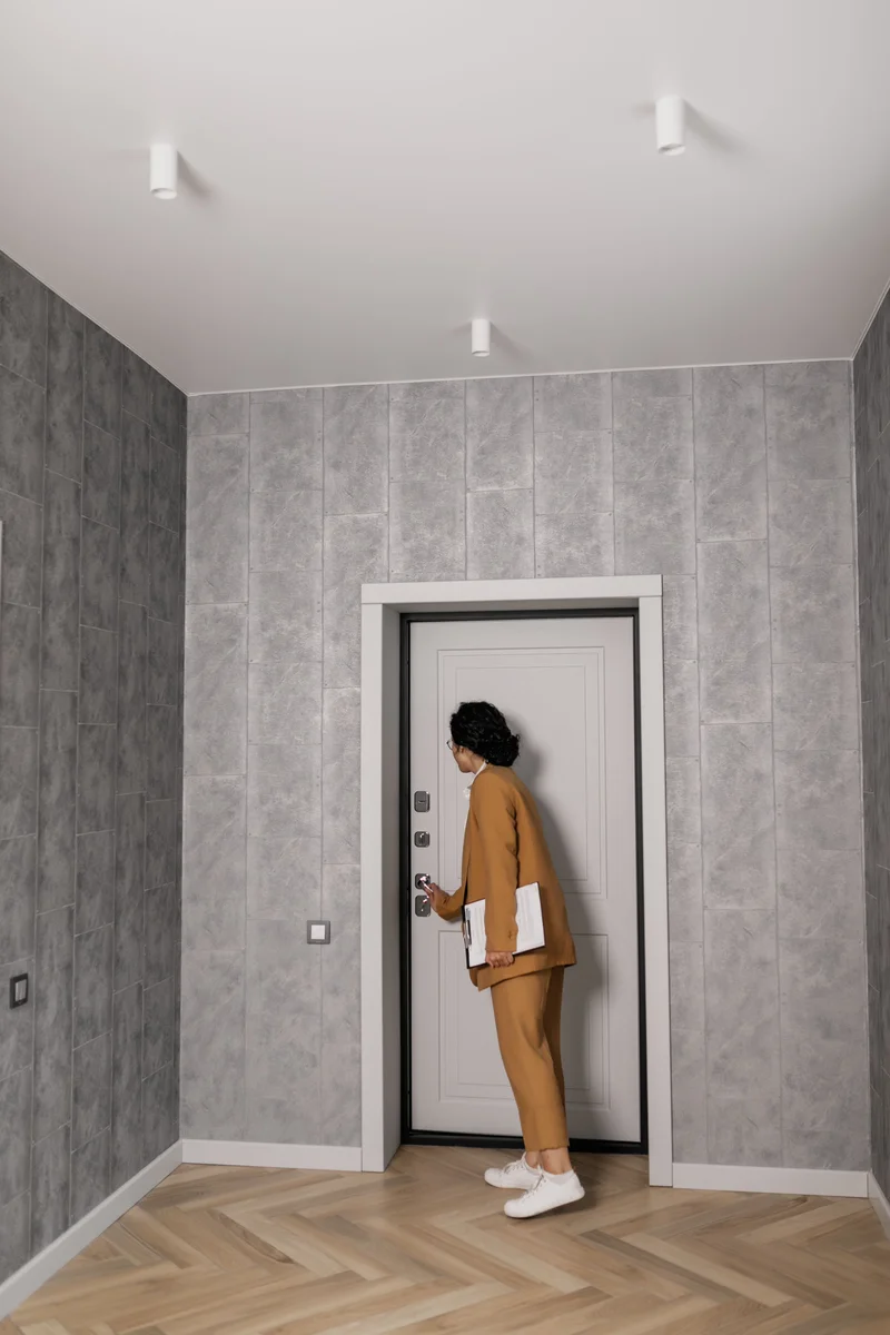 Person holding a clipboard unlocking the door of an empty apartment