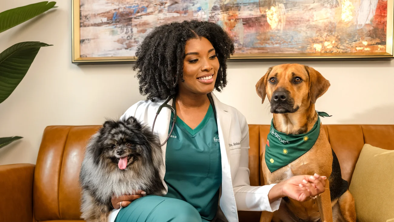 Dr. Aziza sitting on a couch with 2 dogs. 