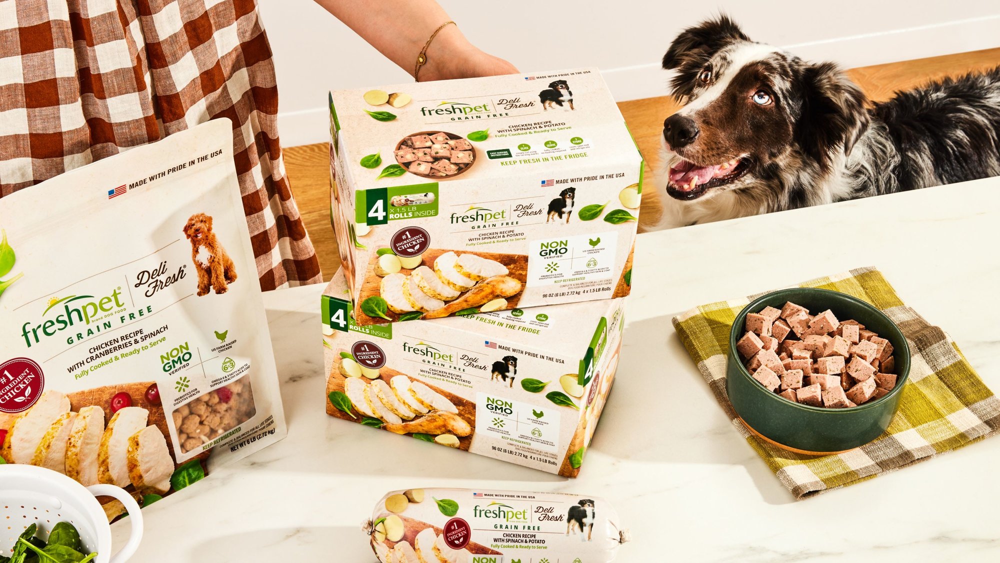 2 Boxes of Freshpet Deli Fresh on a table with a dog looking on. 