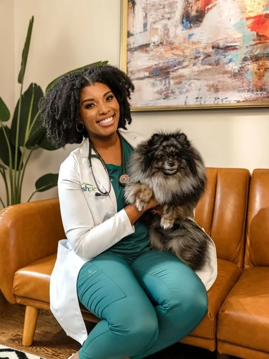 Dr. Aziza Glass sitting on a sofa with a dog