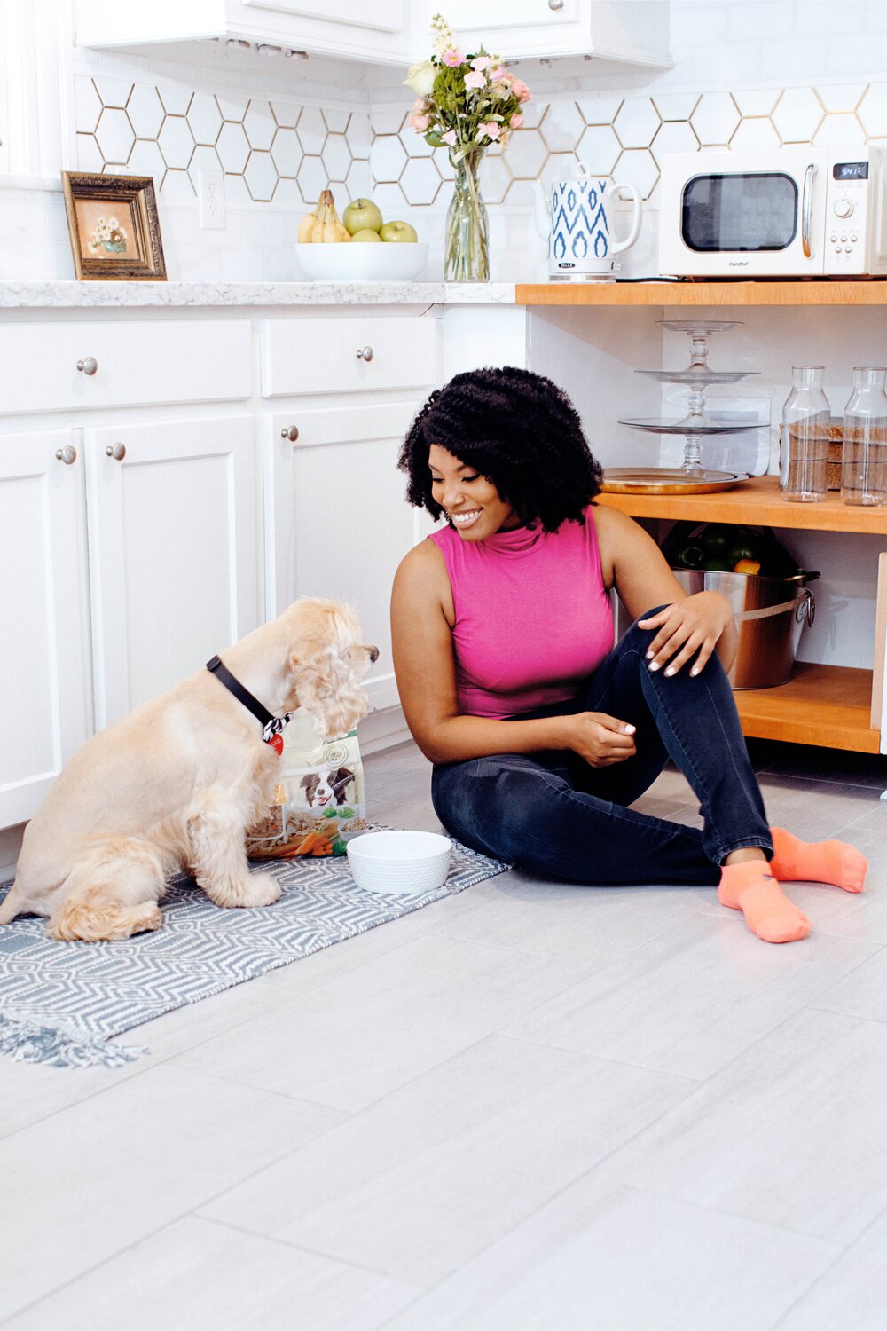 Dr. Aziza Glass sitting next to a dog with a bowl of Freshpet