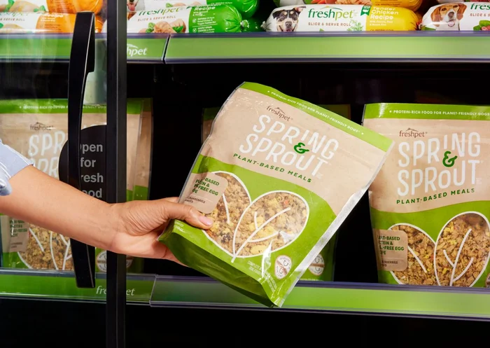 A bag of Freshpet Spring & Sprout being taken from a refrigerator.