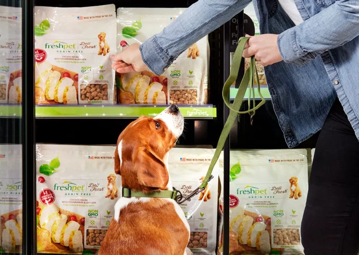 A person with their dog removing a bag of Freshpet Deli Fresh from a refrigerator.