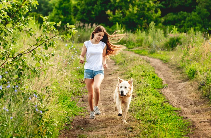 A young woman jogging with her dog on a trail. 