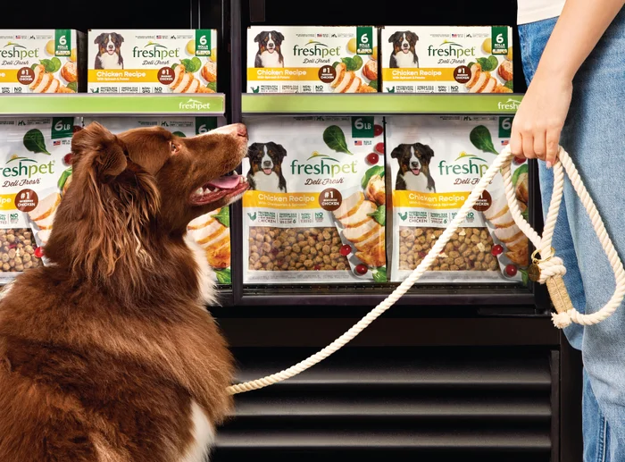 A person with their dog removing a bag of Freshpet Deli Fresh from a refrigerator.
