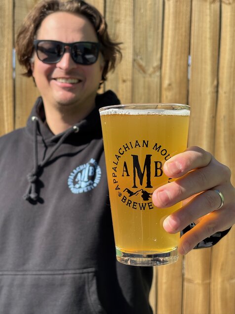 man holding glass of beer that says, "Appalachian Mountain Brewery"