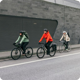 3 mensen op een fiets met VAUDE accessoires in een stedelijke omgeving.