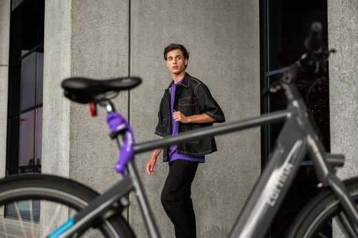 Scholier loopt naar zijn geparkeerde fiets om zijn fiets van het fietsslot te halen in een stedelijke omgeving. 