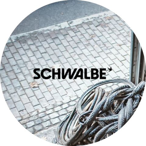 Logo van het merk Schwalbe met achtergrond van een garage met banden erin.