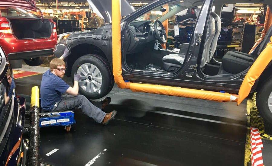 Subaru worker installing a component on a vehicle body on the assembly line