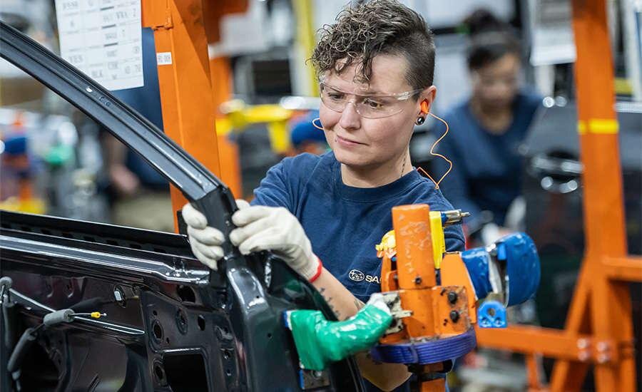 Subaru assembly worker fitting a component to a vehicle door frame