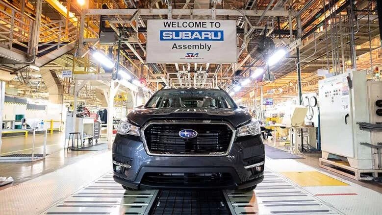 Subaru vehicle on the assembly line beneath a Welcome to Subaru Assembly sign