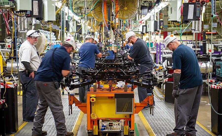 Subaru workers assembling a vehicle chassis module on the production line