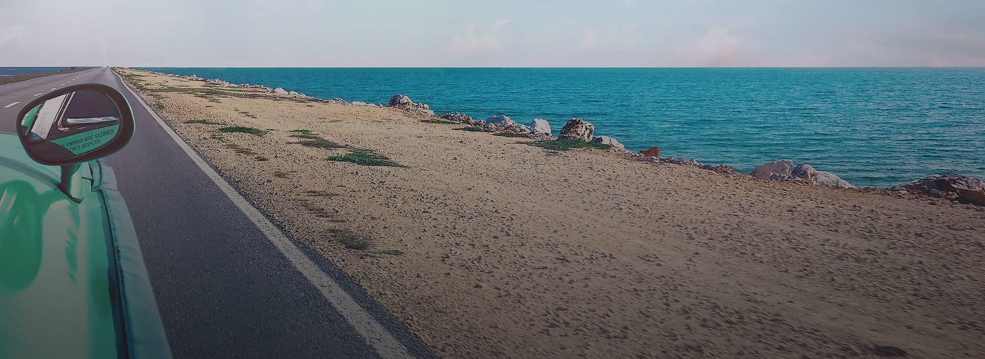 A car on a road with sea on the background