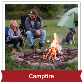 Man, child and dog sitting outside next to a campfire and roasting marshmallows