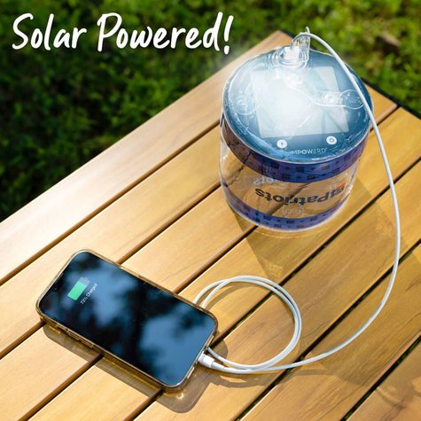 SoLantern Air Inflatable Solar Lantern & Charger on a table charging in the sun while charging a cell phone