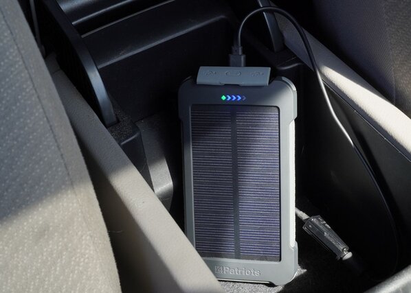 A Patriot Power Cell-CX sitting in the cup holder of a car charging from the sun