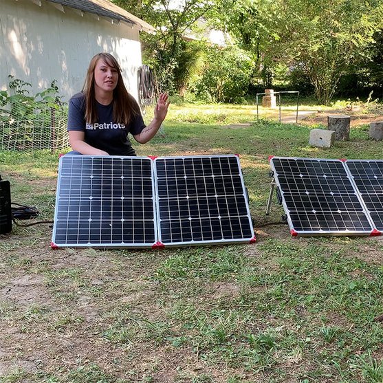 4Patriots employee outside with 2 Patriot Power Generator 100-watt folding solar panels
