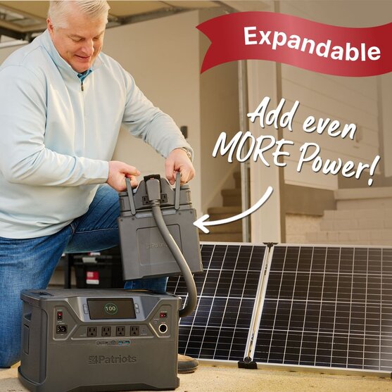 Man outside using the NEW Patriot Power Generator 2000X Power Station Expansion Pack attached to the Patriot Power Generator 2000X next to solar panel. Expandable and even more power!