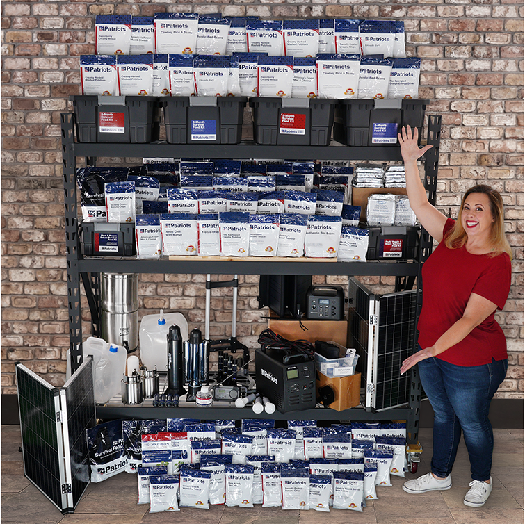 Woman displaying contents of the Patriot Platinum Survival Package including solar generators, panels, water filtration systems, and one year of emergency food.
