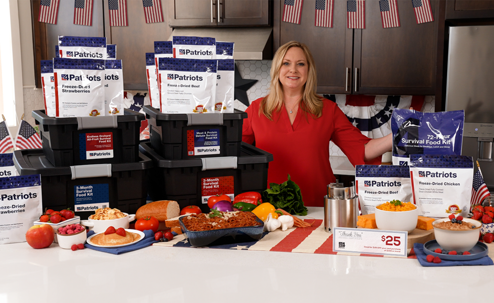 A woman standing in her kitchen with 4 totes of survival food for 4Patriots Memorial Day Offer