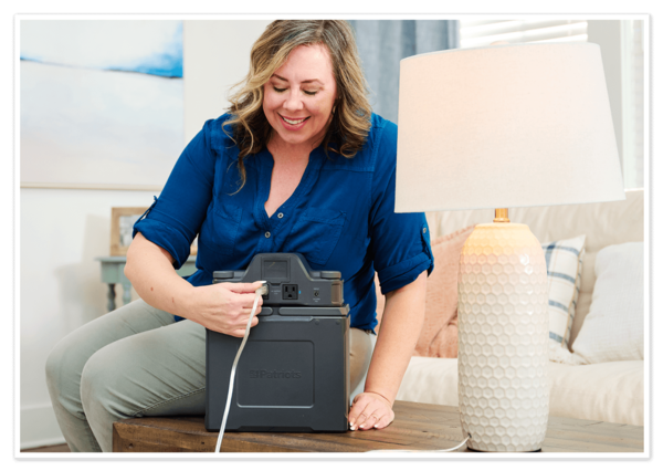 Woman powering lamp by plugging it into the Patriot Power Generator 2000X Expansion Pack