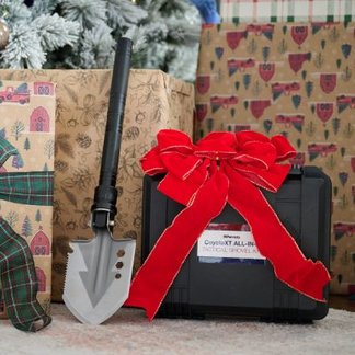 Tactical all in 1 shovel sitting by presents under a Christmas tree. 