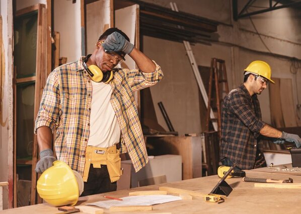 A construction worker wiping sweat off his forehead as he works outside in the heat