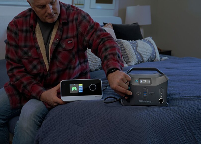 A man uses his Patriot Power Sidekick solar generator to power his CPAP machine in his bedroom during a blackout.