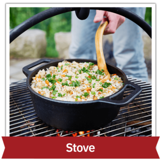 Person's hand mixing food on a stove over a fire outside