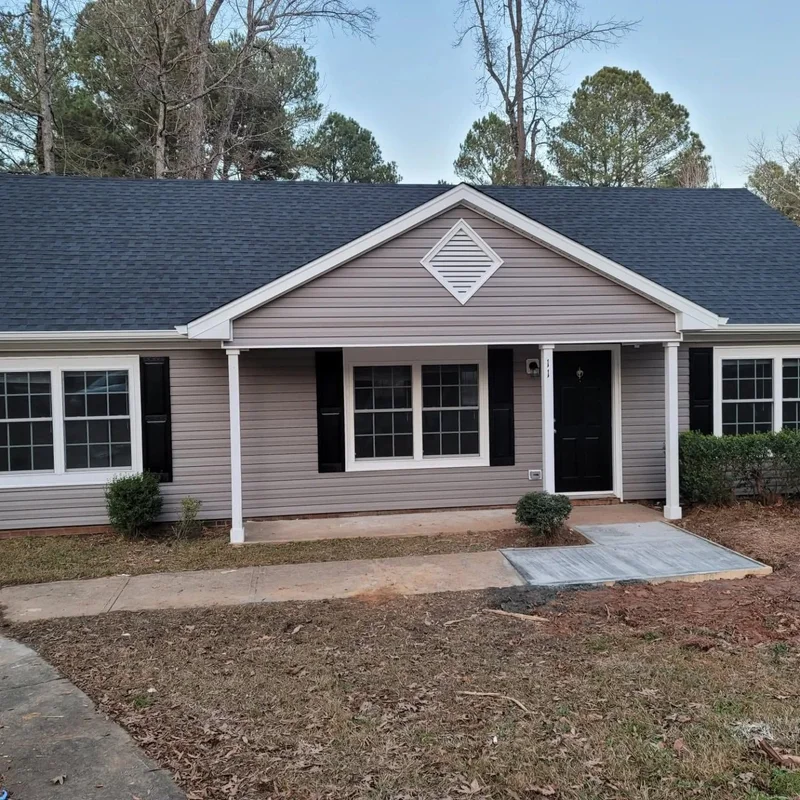 Gray-sided ranch home with black shutters and dark shingle roof