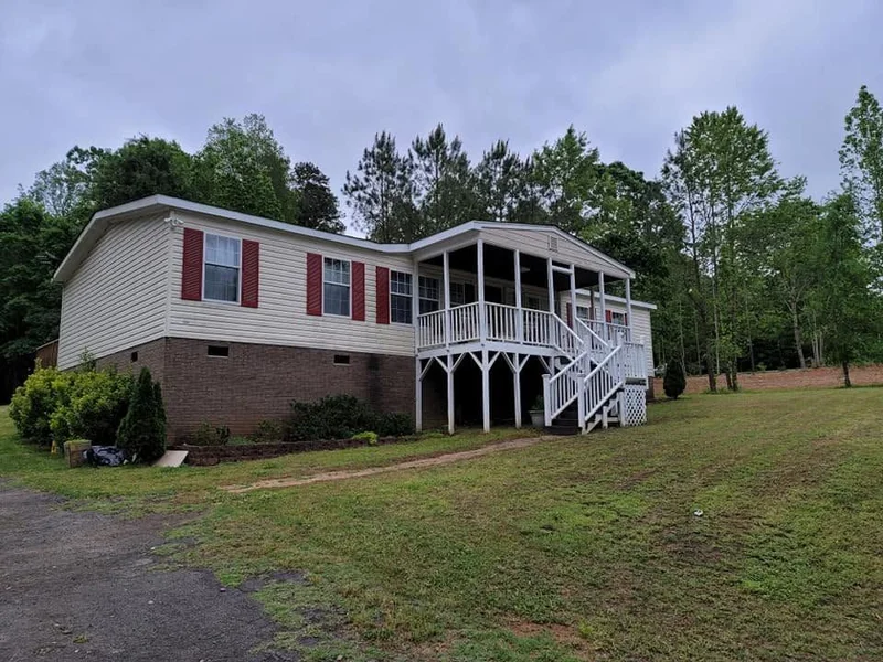 Cream manufactured home with red shutters and white porch railings