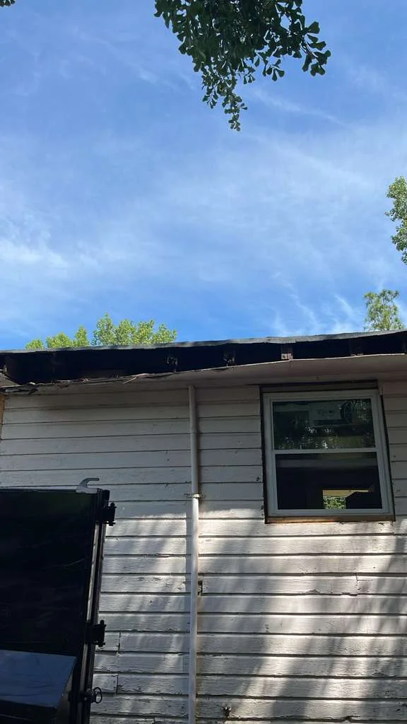 Rotted roof edge and fascia above a window on an older white wood-sided house
