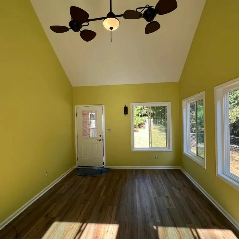 Renovated room with yellow walls, vaulted ceiling, and wood-look flooring