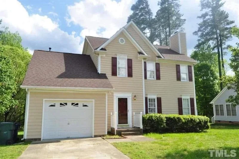 Two-story tan home with attached garage and red front door