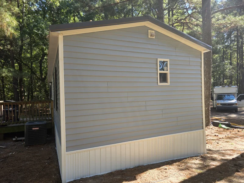 Light gray vinyl-sided manufactured home with white skirting and outdoor HVAC unit